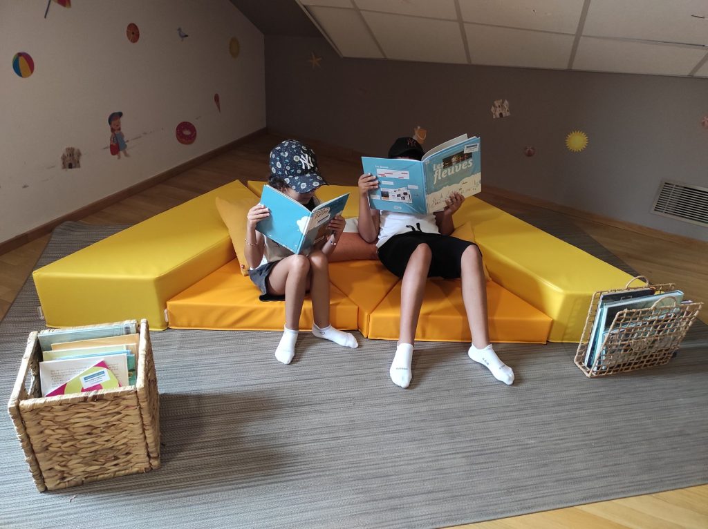 deux enfants qui jouent dans l'espace ludique dans le musée avec deux livres